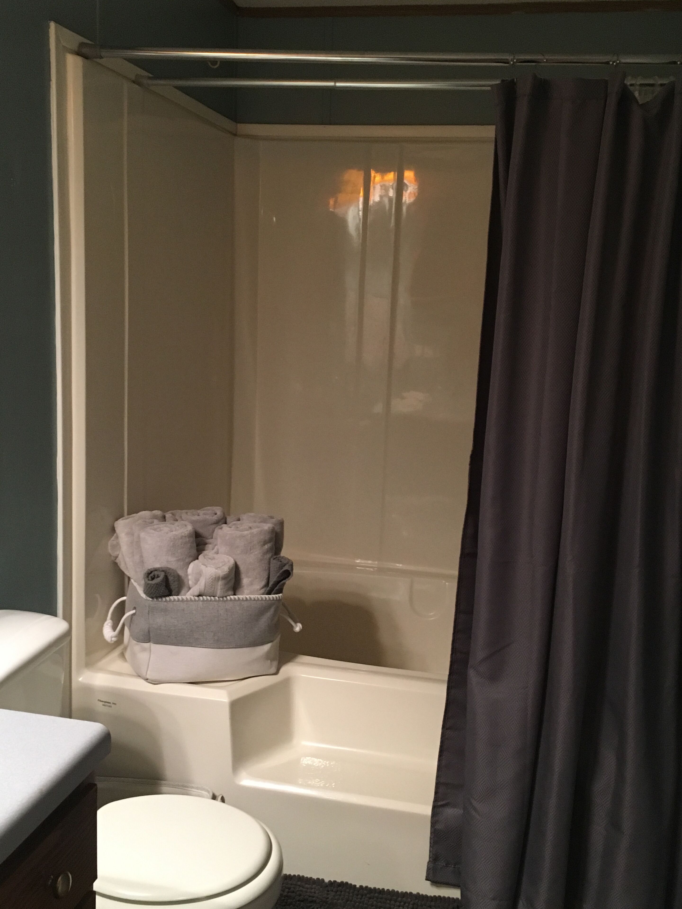 A bathroom with a bathtub, a toilet, and a towel rack with towels.