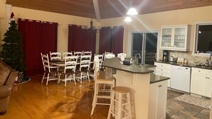 A spacious kitchen with a central island, white cabinetry, and a dining area with white chairs. - Luxury Panorama home on the hill (Panorama)
