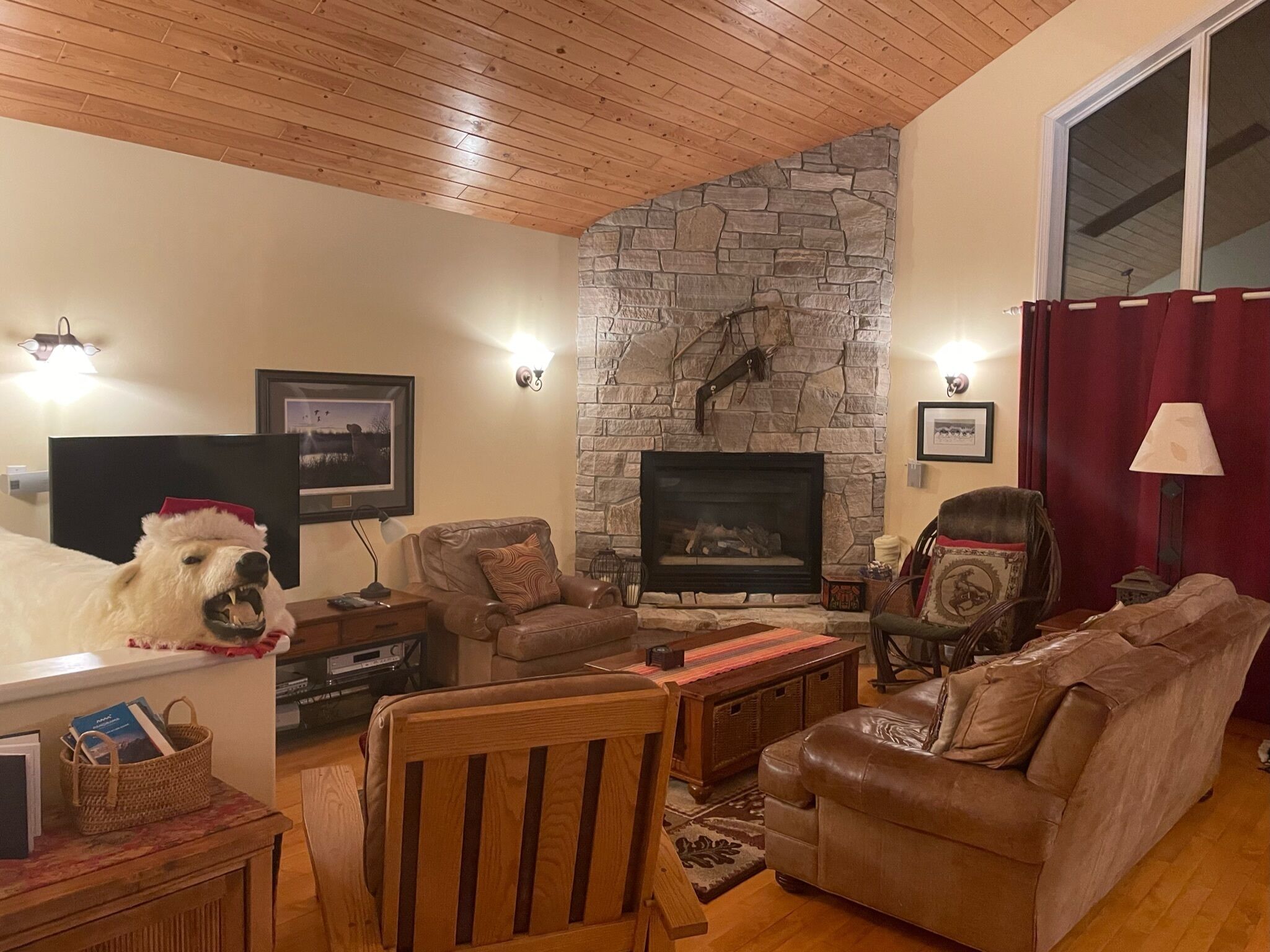 A cozy living room with a stone fireplace, leather sofas, and a television.