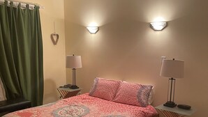 A bedroom with a bed, two bedside tables with lamps, a ceiling fan, and a green curtain. - Luxury Panorama home on the hill (Panorama)
