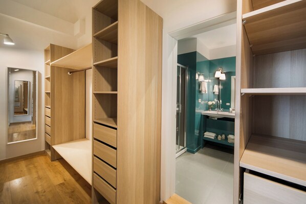 A modern interior with wooden shelving units, a walk-in closet, and a bathroom with a teal accent wall.