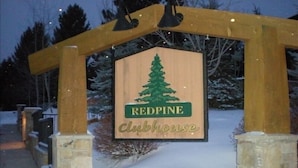 A wooden sign with a green pine tree and the words "Redpine Clubhouse" against a snowy background. - Remodeled 1 Bedroom Condo Short walk to Cabriolet Mountain views from unit (Park City)