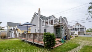 A two-story house with a porch, a covered outdoor seating area, and a garage.