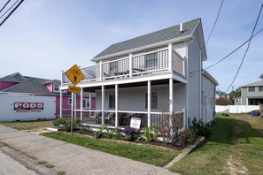A two-story house with a balcony, a 'For Rent' sign, and a 'PODS Moving & Storage' sign.
