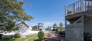 A residential area with a paved pathway, a wooden deck, and a house with a balcony.