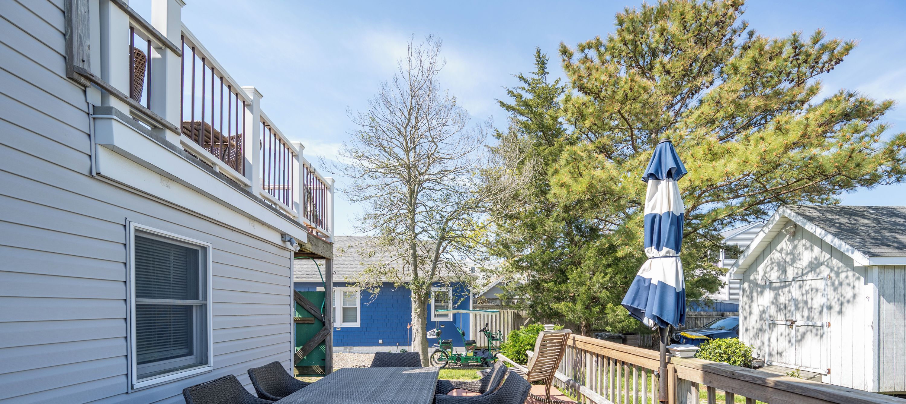 A deck with outdoor furniture, a wooden railing, and a blue umbrella.