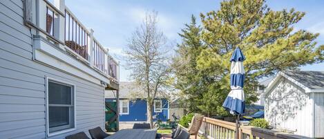 A deck with outdoor furniture, a wooden railing, and a blue umbrella.
