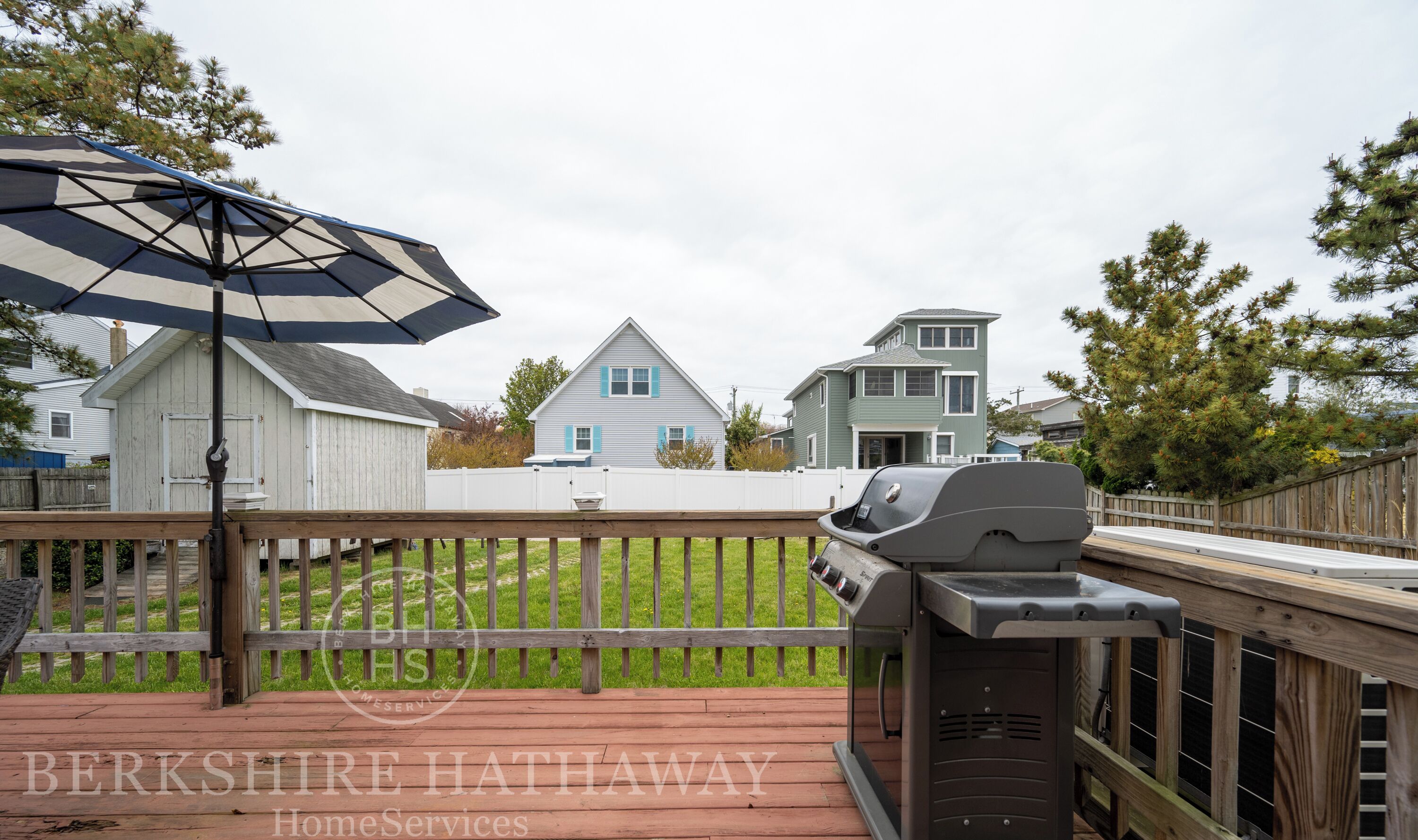 Une terrasse en bois avec un barbecue et un parasol.