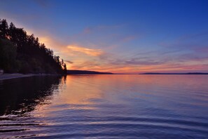 A calm lake at sunset with a forested shoreline.