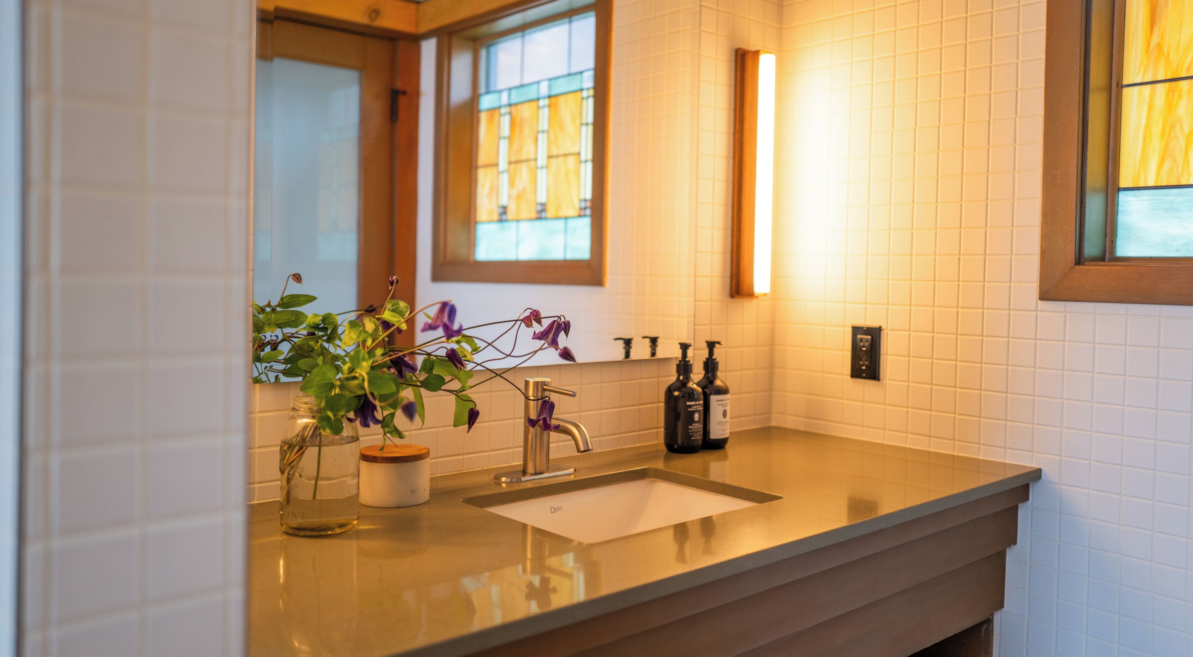 A bathroom with a sink, mirror, and window.