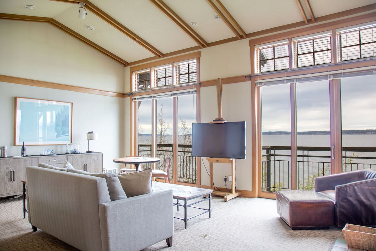 A spacious living room with a large window, a flat-screen TV, and a cozy seating area.