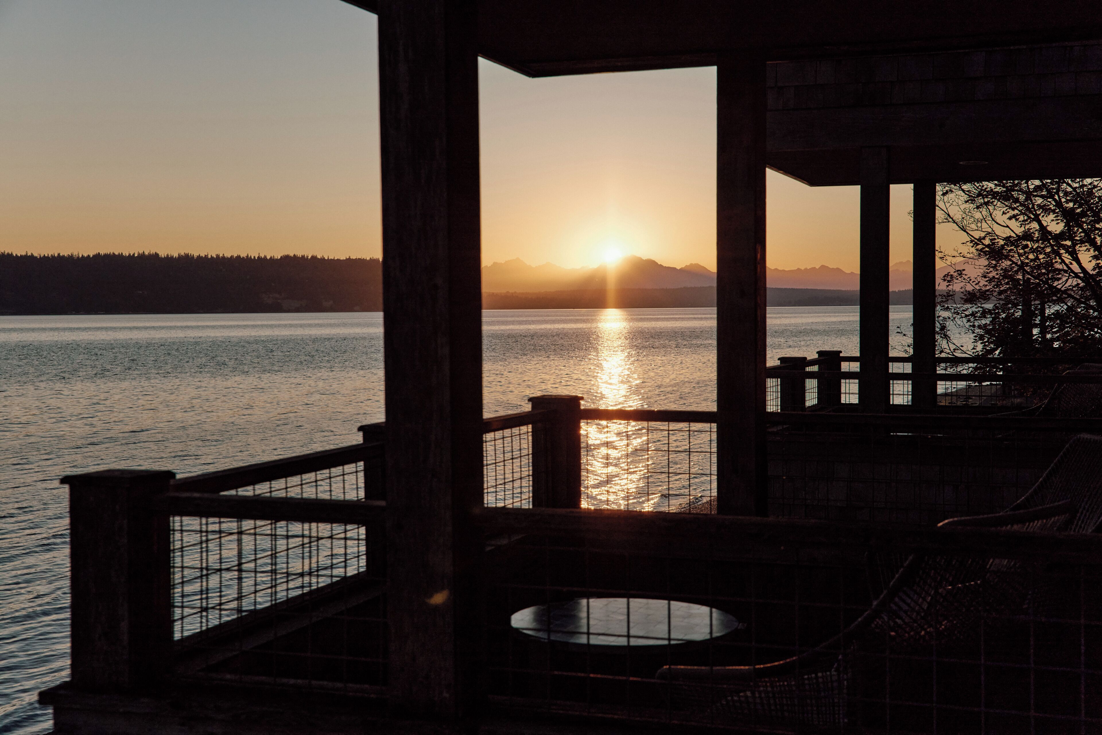 A wooden deck with a view of a sunset over a body of water.