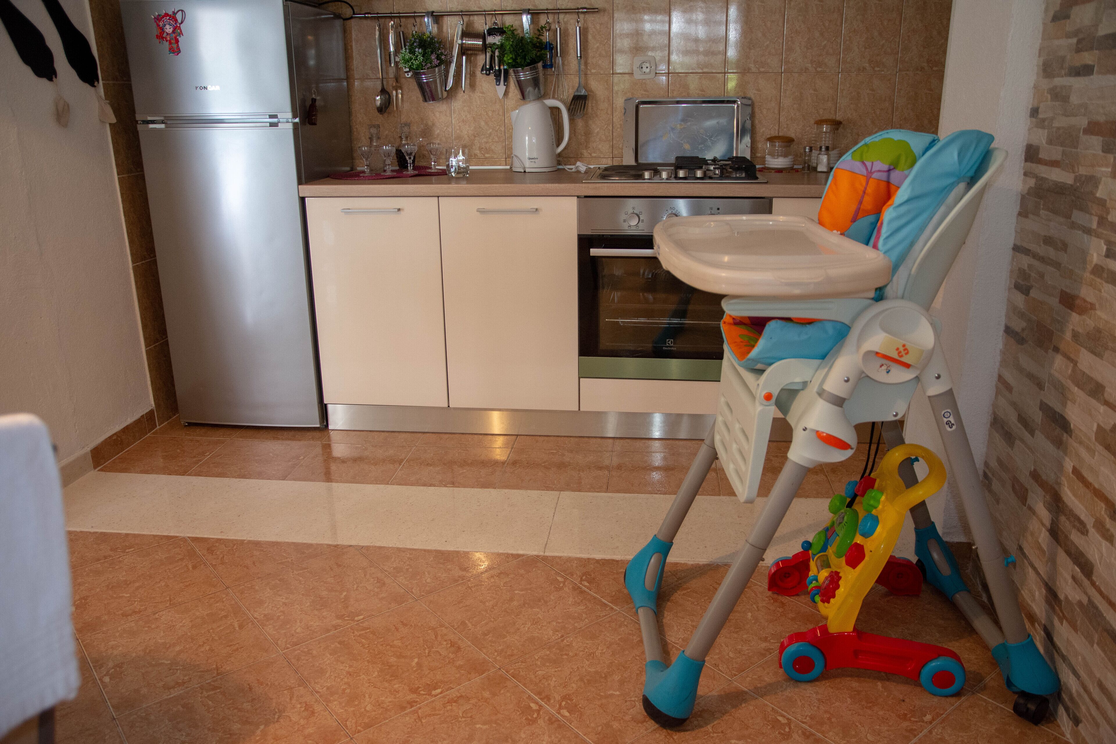 Eine Küche mit Kühlschrank, Backofen und Hochstuhl für Kinder.