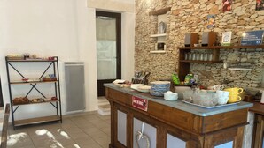 Una barra de desayuno con un fondo de pared de piedra, un estante metálico con pasteles y un cartel que indica el servicio 'Botte du Ruisseau'.