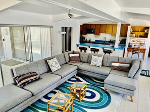 Un salon moderne avec un canapé d’angle gris, un tapis à motifs et une table basse en verre.