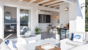 Un espacio habitable moderno y abierto con comedor, muebles blancos y un ventanal que da a un balcón.