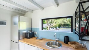 Eine kleine Küche mit eingebautem Toaster, Spüle und Fenster mit Blick auf einen Garten.