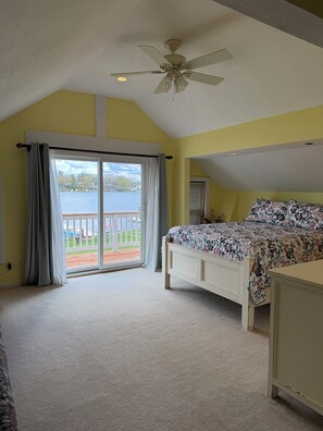 A bedroom with a bed, a ceiling fan, a view of a lake through a sliding glass door, and a balcony. - Vacation at the Lake (Howell)
