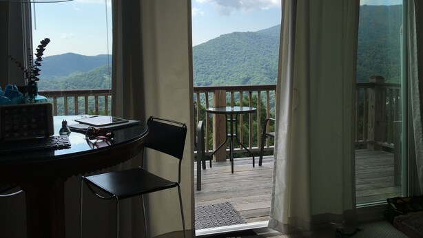 A room with a desk, chair, and a view of a balcony with a table and chairs. - HIGH MOUNTAIN CONDO--PANORAMIC VIEWS! (Seven Devils)