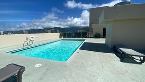 A rooftop pool with a clear view of mountains in the background, a wheelchair-accessible sign, and a lounge chair. - Brand New And Fully Furnished 1 Bedroom Condo (Honolulu)
