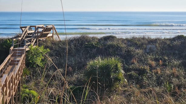 Un muelle de madera que conduce a una playa con vistas al océano.