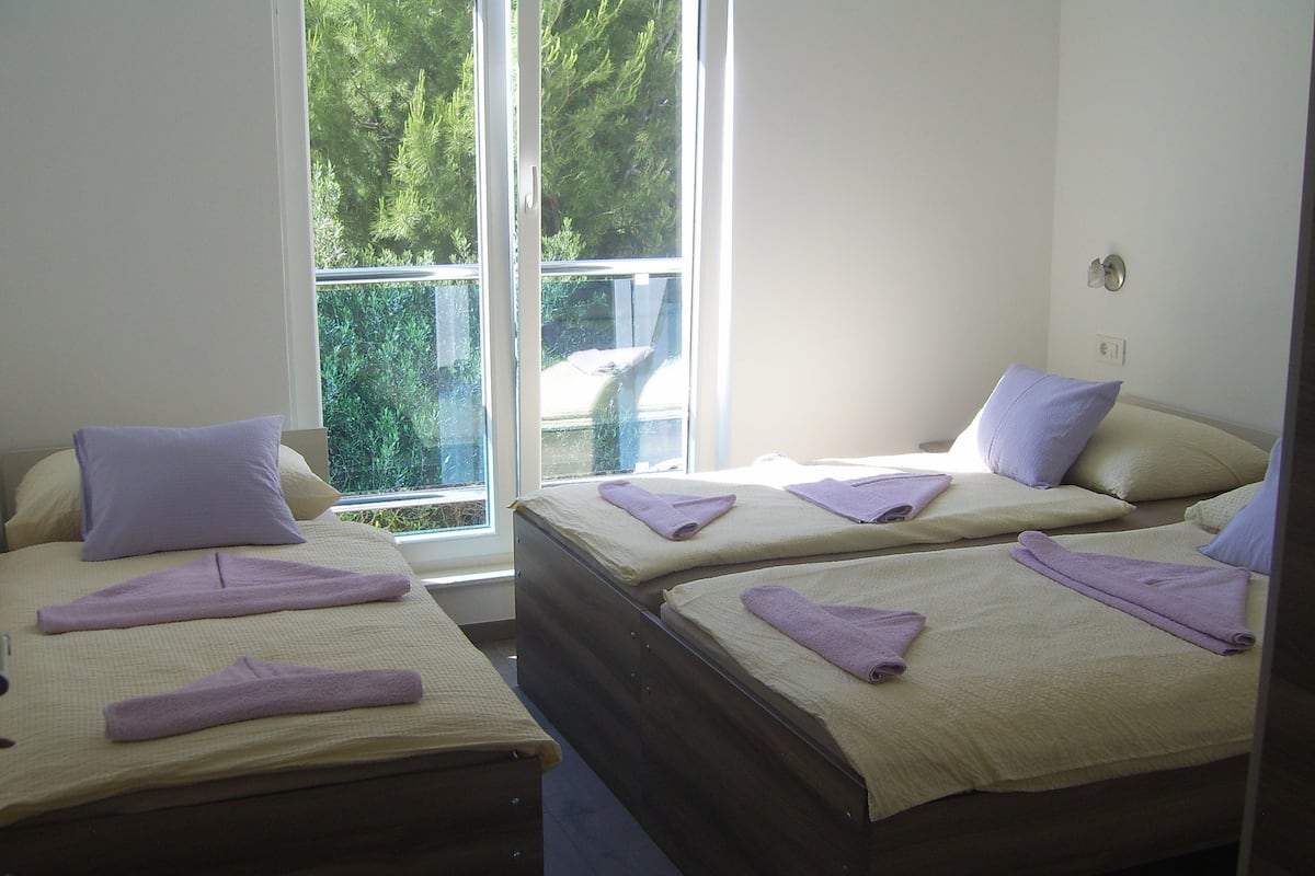 A hotel room with two beds, each with a pillow and a rolled towel.