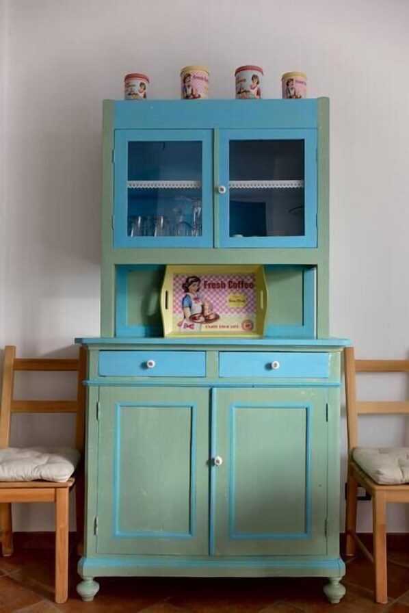 Un mueble color turquesa con dos puertas y una repisa, que contiene una caja etiquetada 'Fresh Coffee'.