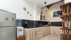 Una cocina equipada con refrigerador, dispensador de agua, microondas y armarios de madera.