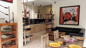 Un salón espacioso con una mesa de comedor de madera dispuesta para una comida, un sofá negro y un cuadro grande en la pared.