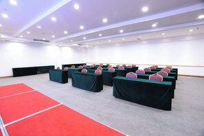A conference room with rows of tables, a red carpet, and a white wall. - May King Grand Hotel (Guangzhou)
