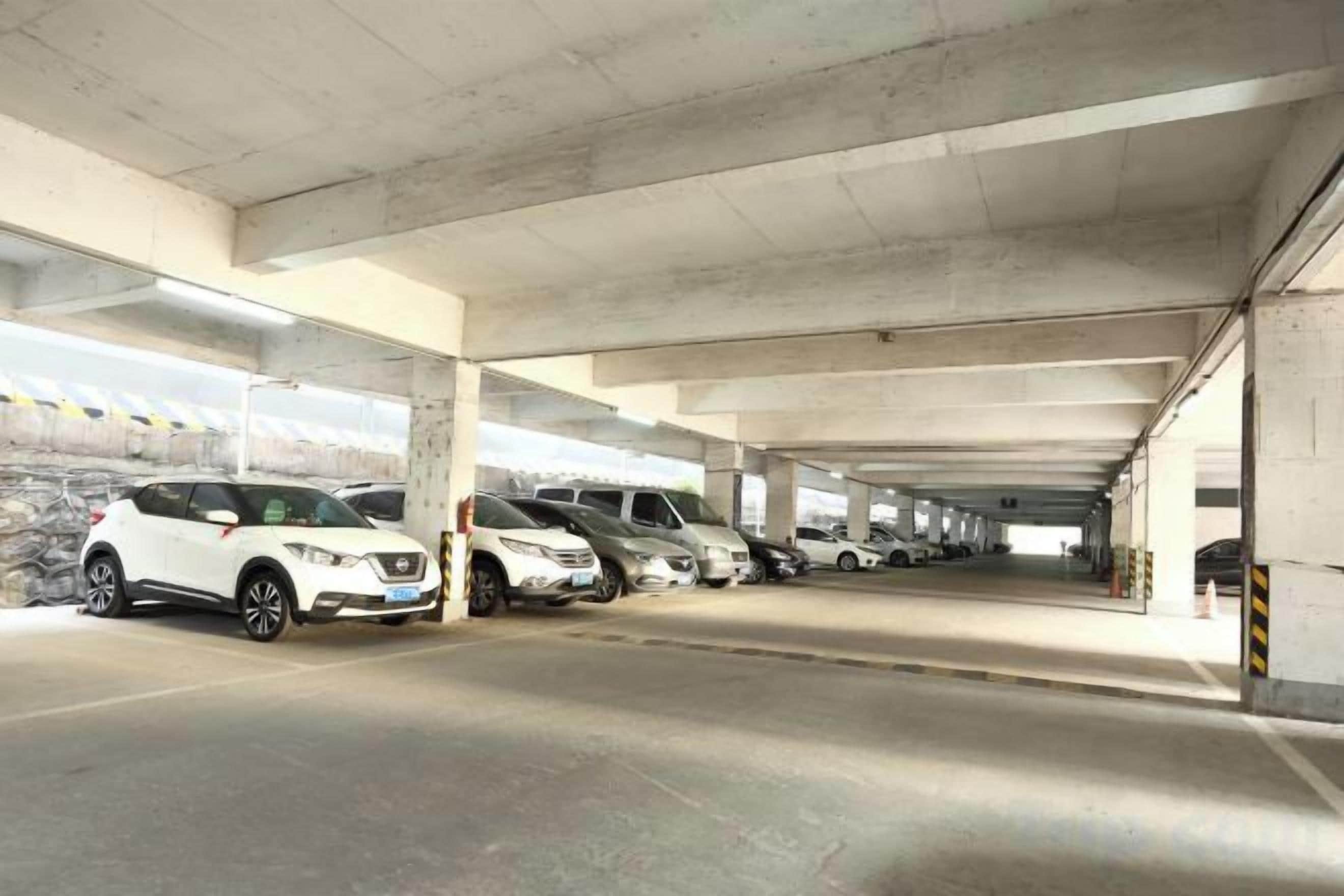 A multi-level parking garage with concrete pillars and a row of parked cars.