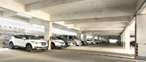 A multi-level parking garage with concrete pillars and a row of parked cars.