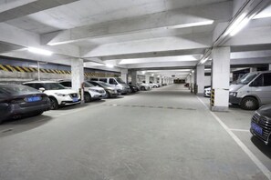 A multi-level underground parking garage with cars parked in rows, concrete pillars, and overhead lighting. - May King Grand Hotel (Guangzhou)
