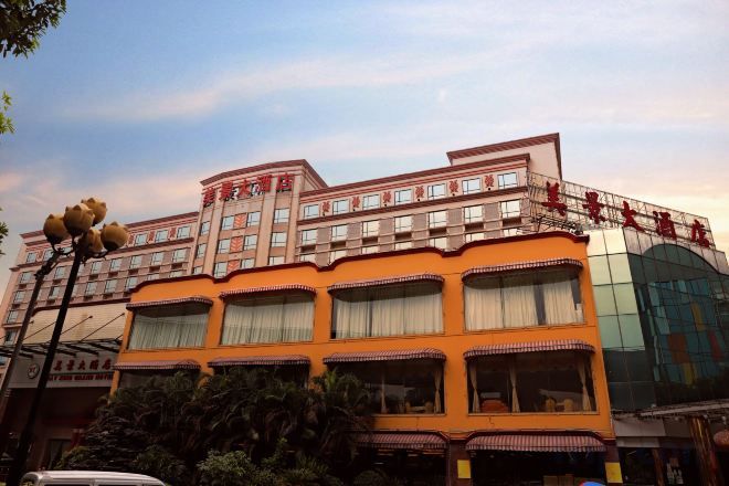 A multi-story hotel with a distinctive orange facade, multiple balconies, and a large glass entrance.