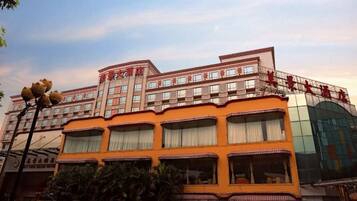Um hotel com vários andares, fachada laranja marcante, várias varandas e uma grande entrada de vidro.