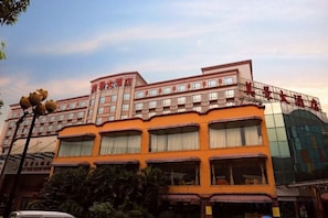 A multi-story hotel with a distinctive orange facade, multiple balconies, and a large glass entrance. - May King Grand Hotel (Guangzhou)