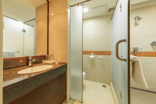 Un baño moderno con ducha de vidrio, lavamanos de mármol y un perchero para toallas.