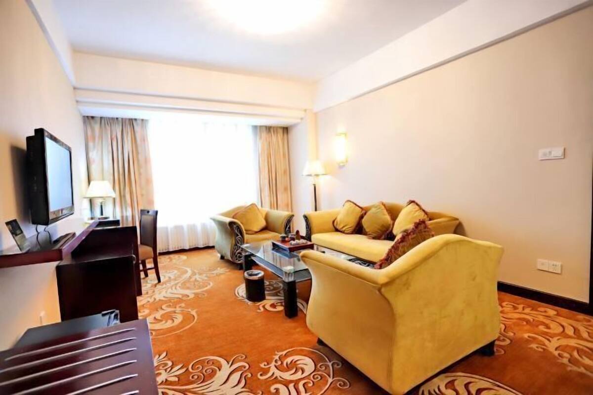 A hotel room with a sofa, a coffee table, a TV, and a desk.