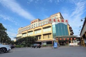 A multi-story hotel with a prominent entrance, a parking area, and a clear sky. - May King Grand Hotel (Guangzhou)