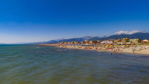 Una playa con edificios al fondo y montañas en la distancia.