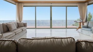 Un salón amplio con un balcón grande, un sofá, una silla y una mesita.