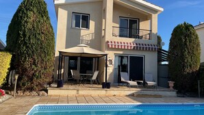 Ein zweigeschossiges Haus mit Pool, Sitzgelegenheiten im Freien und einer überdachten Terrasse.