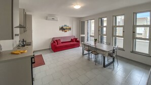 A modern kitchen with a dining area, a red sofa, and large windows. - APARTMENT 50 MT FROM THE PESCOLUSE BEACH (Pescoluse)