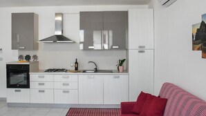A compact kitchen with white cabinets, a gas stove, and a built-in oven. - APARTMENT 50 MT FROM THE PESCOLUSE BEACH (Pescoluse)