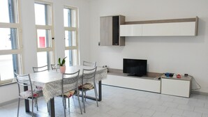 A modern kitchen with a dining table, chairs, a TV, and a built-in cabinet. - APARTMENT 50 MT FROM THE PESCOLUSE BEACH (Pescoluse)