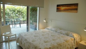 Ein Schlafzimmer mit einem großen Bett, einem Schreibtisch und einem Stuhl, einem Fenster mit Blick ins Grüne und einem Bild an der Wand.