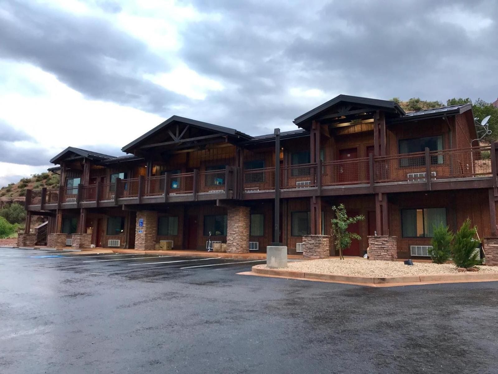 A multi-story lodge with a rustic wooden exterior, balconies, and a parking lot.