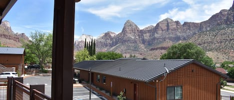 A wooden building with a metal roof, surrounded by a parking area and a mountain backdrop.