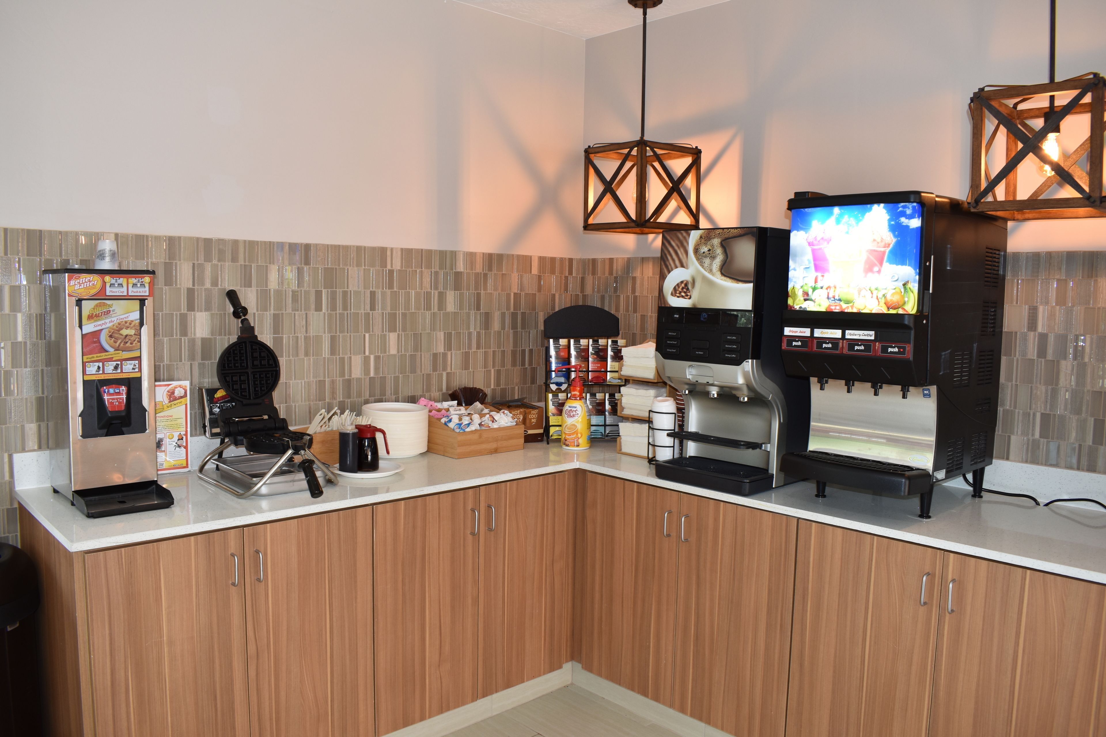A modern kitchen with a waffle maker, coffee machine, and a TV displaying a coffee advertisement.