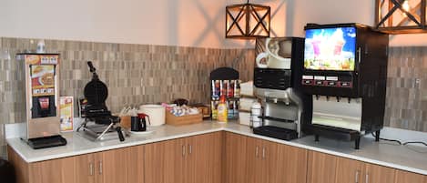 A modern kitchen with a waffle maker, coffee machine, and a TV displaying a coffee advertisement.